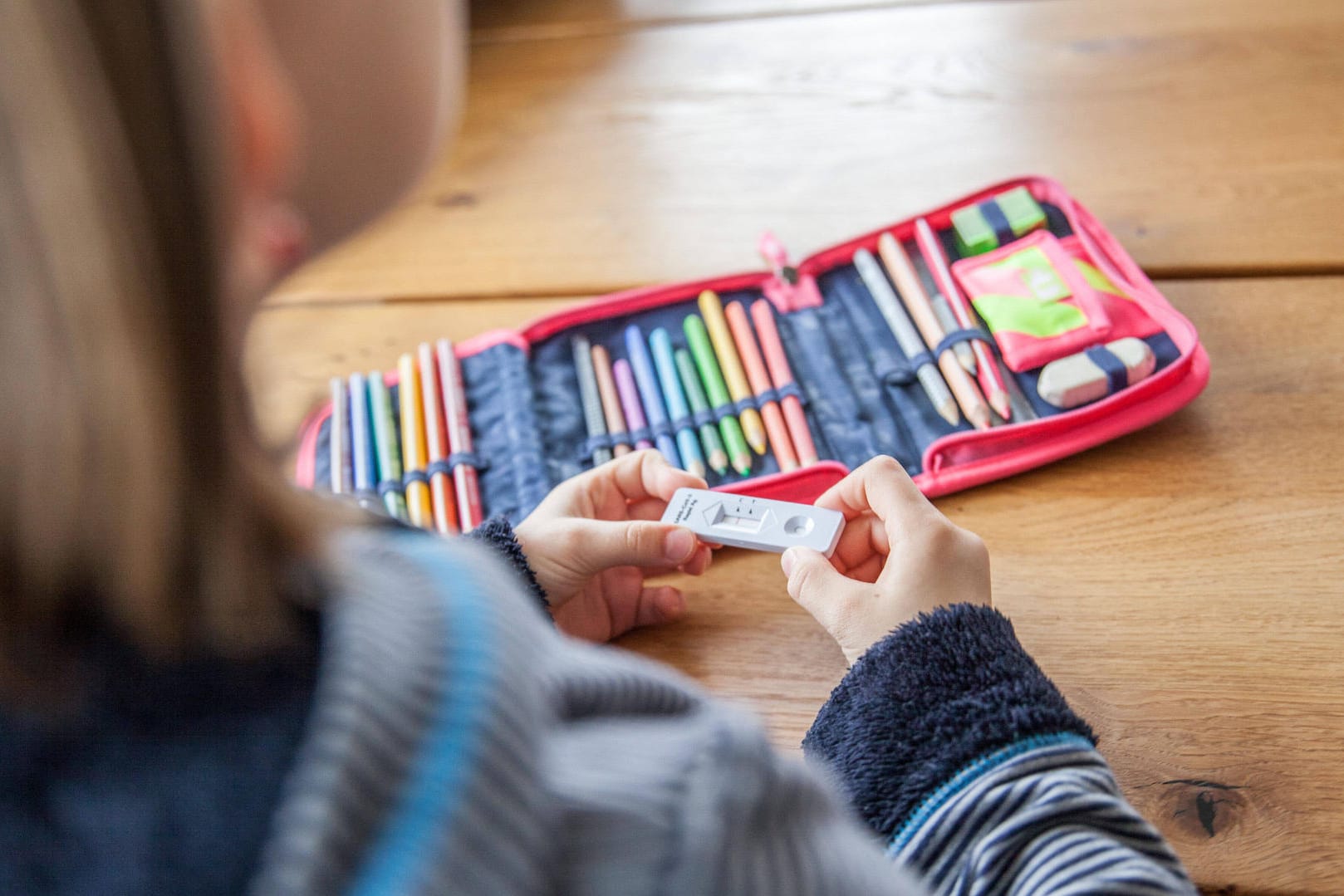 Ein Kind hält einen Antigen-Test in der Hand (Archivbild): In Köln müssen sich Schulkinder vor dem Unterricht auf Corona testen.