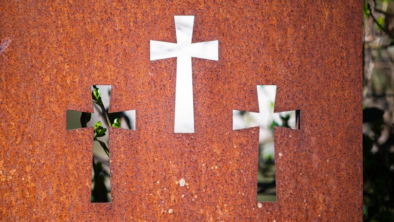 Kreuzsymbole auf einem Friedhof (Symbolbild): In Leverkusen wird ein Polizeiaufgebot für die Trauerfeier für das Oberhaupt einer Großfamilie im Einsatz sein.