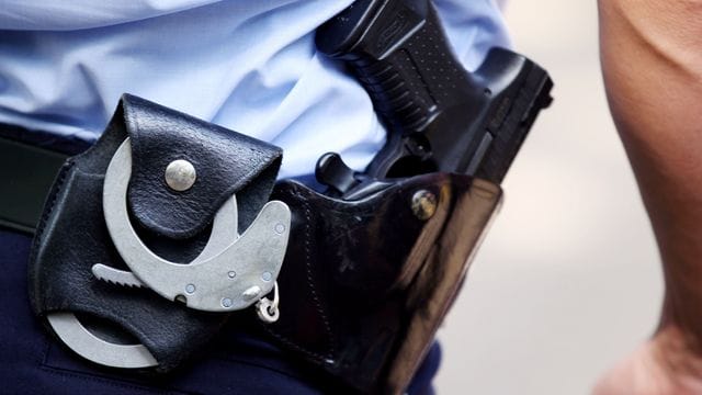 Ein Polizist mit Handschellen und Pistole am Gürtel (Archivbild): In Wuppertal haben bis zu 20 Personen etwa Warnbaken auf die Straße geworfen. Ein Polizist mit Handschellen und Pistole am Gürtel (Archivbild): In Wuppertal haben bis zu 20 Personen etwa Warnbaken auf die Straße geworfen.