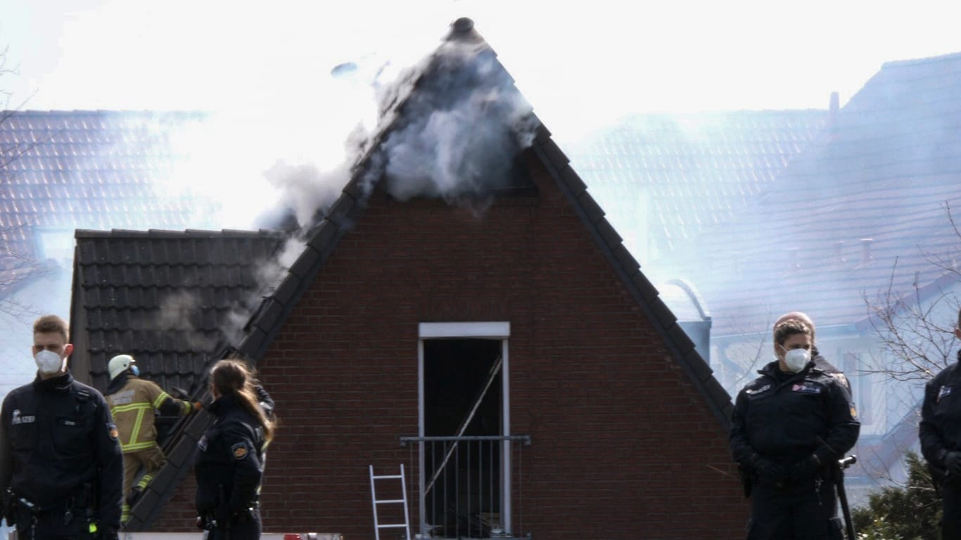 Polizisten stehen vor einem Haus, aus dessen Dachgiebel Rauch aufsteigt: Beim dem Brand des Einfamilienhauses sind nach Feuerwehrangaben vier Menschen getötet worden.
