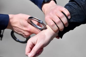 Ein Polizist legt einer Person eine Handschelle an (Symbolbild): Der Stiefvater des Jungen wurde festgenommen.