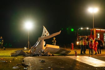 Sportflugzeug abgestürzt: Einsatzkräfte stehen neben einem abgestürzten Flugzeug auf dem Rollfeld des Flugplatzes in Kulmbach.