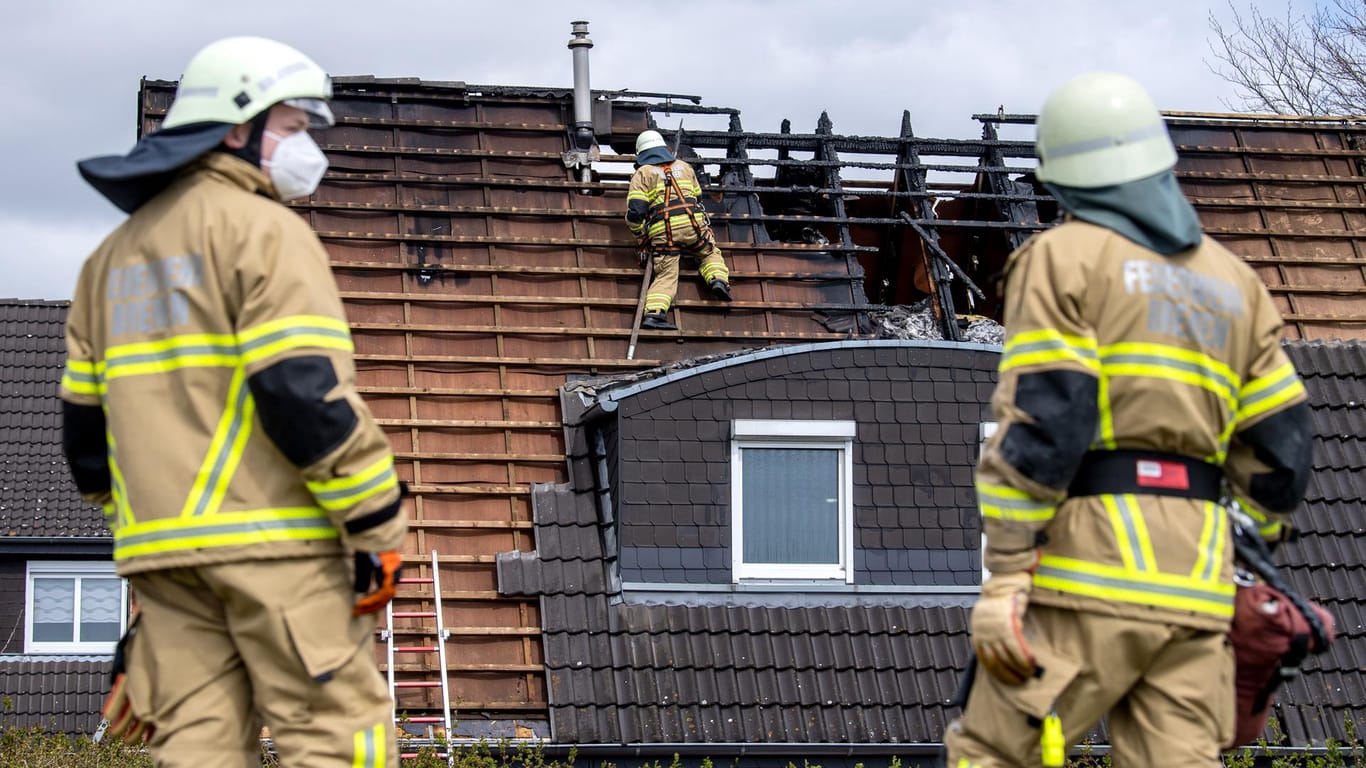 Einsatzkräfte der Feuerwehr stehen vor einem durch Feuer beschädigten Haus im Stadtteil Mahndorf: Beim Brand eines Einfamilienhauses in Bremen sind vier Menschen getötet worden.