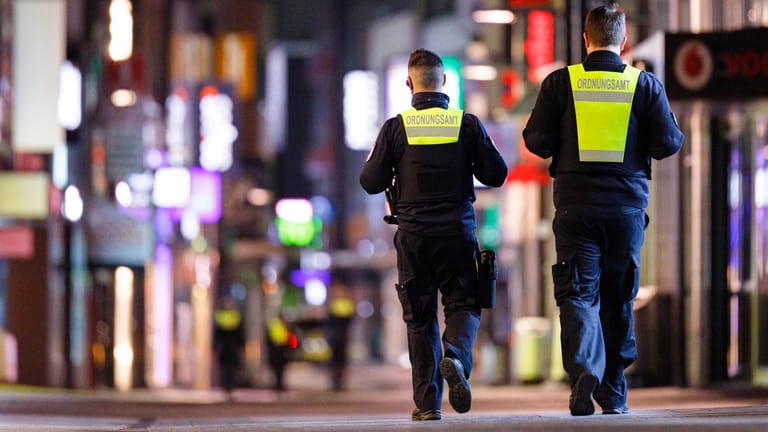 Polizisten laufen in Köln Streife (Archivbild). In vielen Städten gibt es seit Samstag eine nächtliche Ausgangssperre.