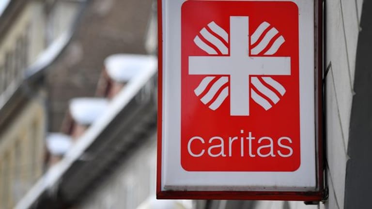 Das Logo der Caritas hängt an einem Gebäude (Symbolbild): Die Direktorin der Caritas will zur Normalität im Alltag zurückfinden.