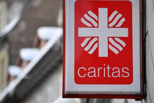 Das Logo der Caritas hängt an einem Gebäude (Symbolbild): Die Direktorin der Caritas will zur Normalität im Alltag zurückfinden.