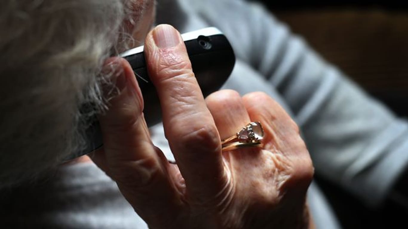 Eine Rentnerin hält ein Telefon in der Hand (Symbolbild): Eine Bremer Seniorin wurde Opfer eines Raubüberfalls.