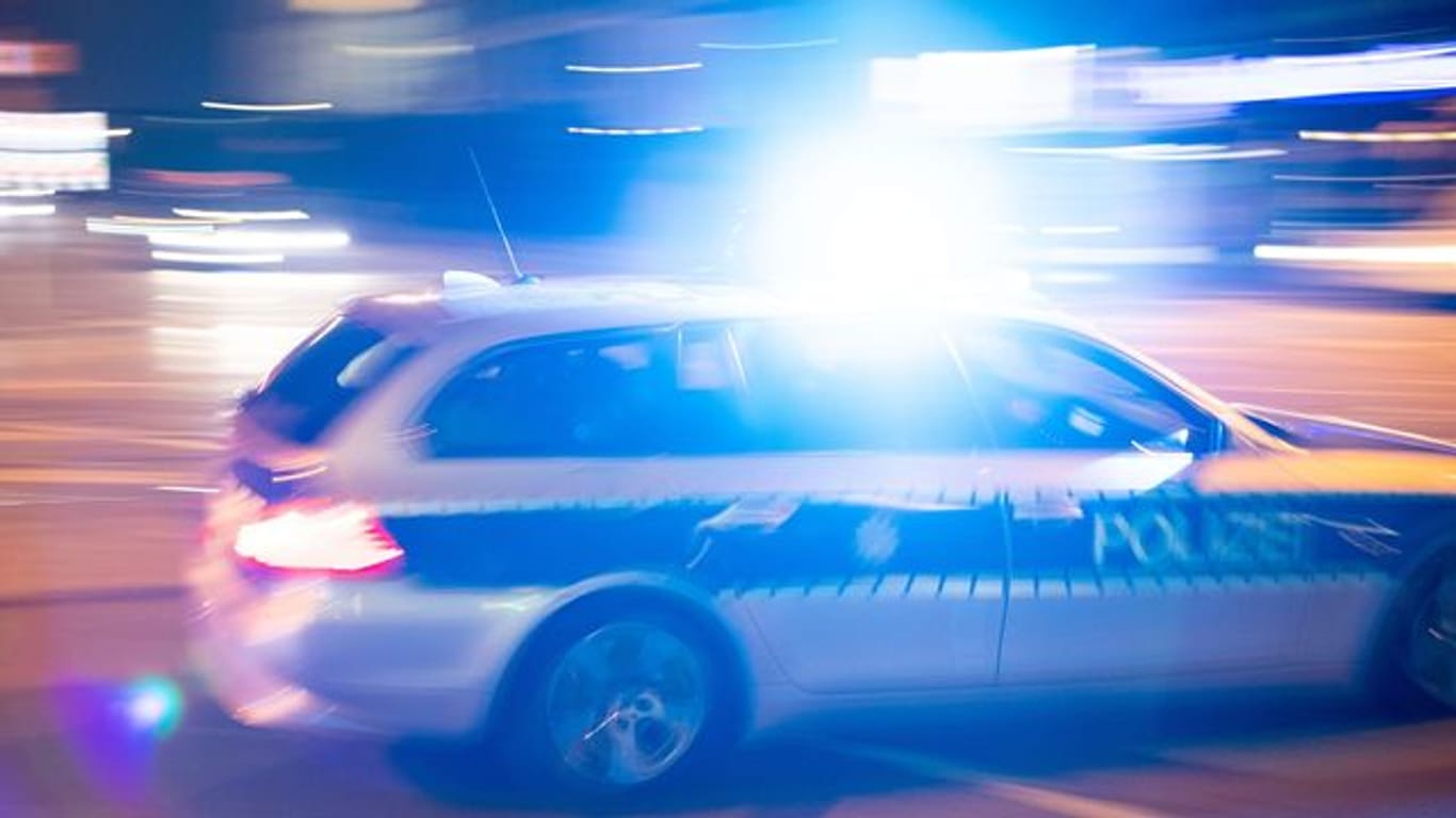 Ein Polizeiauto fährt mit Blaulicht über eine Straße: Auf ihrer Flucht haben zwei Einbrecher Streifenwagen gerammt.