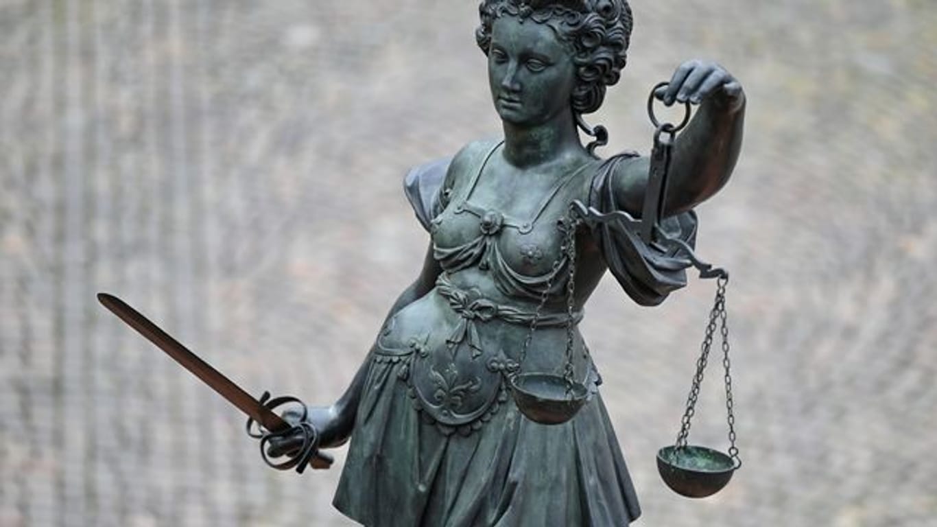 Die Statue der Justitia steht mit einer Waage und einem Schwert in der Hand (Archivbild): In Frankfurt stehen vier junge Männer nach einer Auseinandersetzung auf einem Spielplatz vor Gericht, bei der Schüsse gefallen sind.