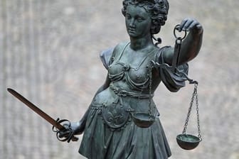 Die Statue der Justitia steht mit einer Waage und einem Schwert in der Hand (Archivbild): In Frankfurt stehen vier junge Männer nach einer Auseinandersetzung auf einem Spielplatz vor Gericht, bei der Schüsse gefallen sind.