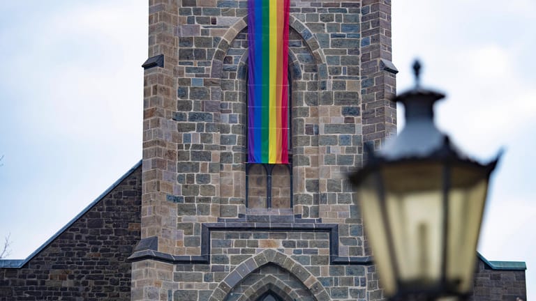 Eine Regenbogenfahne hängt an einer Kirche (Symbolbild): In München musste ein Priesterschüler mutmaßlich gehen, weil er ein Foto mit einem schwulen Reality-TV-Star gepostet hatte.