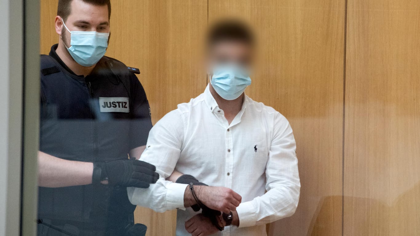 Ein Angeklagter wird in Handschellen in den Gerichtssaal geführt: Zwei Angeklagten wird vorgeworfen, am 16.05.2020 in Stuttgart mit weiteren, bislang unbekannten Tätern drei Demo-Teilnehmer angegriffen zu haben.