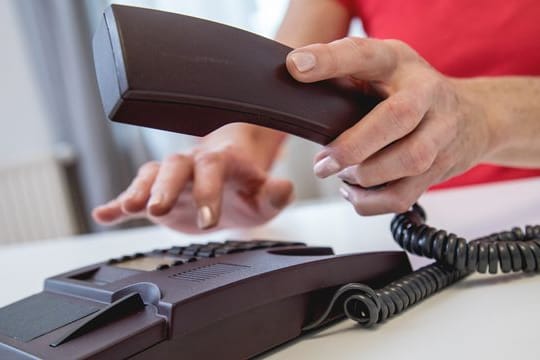 Jemand wählt eine Telefonnummer: Ein Anruf bei der Servicehotline darf für Kundinnen und Kunden nicht teurer sein als ein ganz gewöhnlicher Anruf.