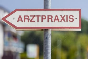 Ein Schild mit der Aufschrift "Arztpraxis" steht an der Straße (Symbolbild): Für Menschen zwischen 60 und 69 Jahren kann das Vakzin von Astrazeneca zur Impfung verwendet werden.