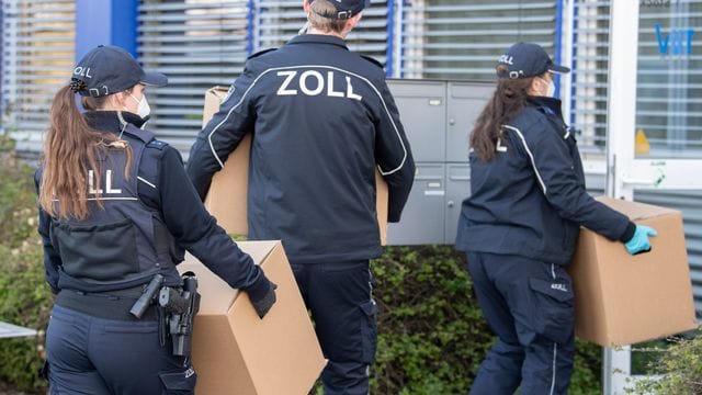 Zollbeamte tragen während einer Razzia bei einem Reinigungsunternehmen leere Kartons zum Transport ins Gebäude (Symbolbild): Zoll und Polizei haben acht illegal beschäftigte Verdächtige festgenommen.