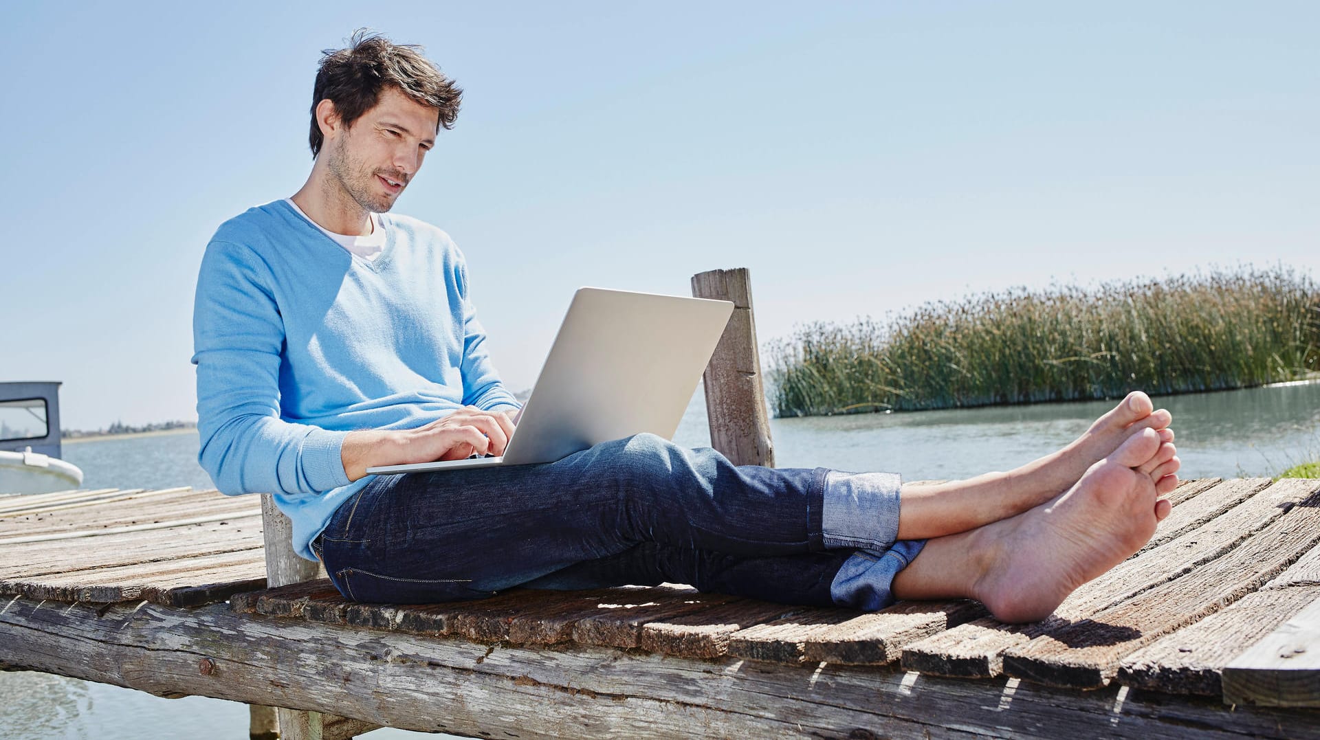 Ein Mann sitzt mit dem Laptop am See: Telefónica/O2 hat neue "Internet to Go"-Tarife im Angebot.