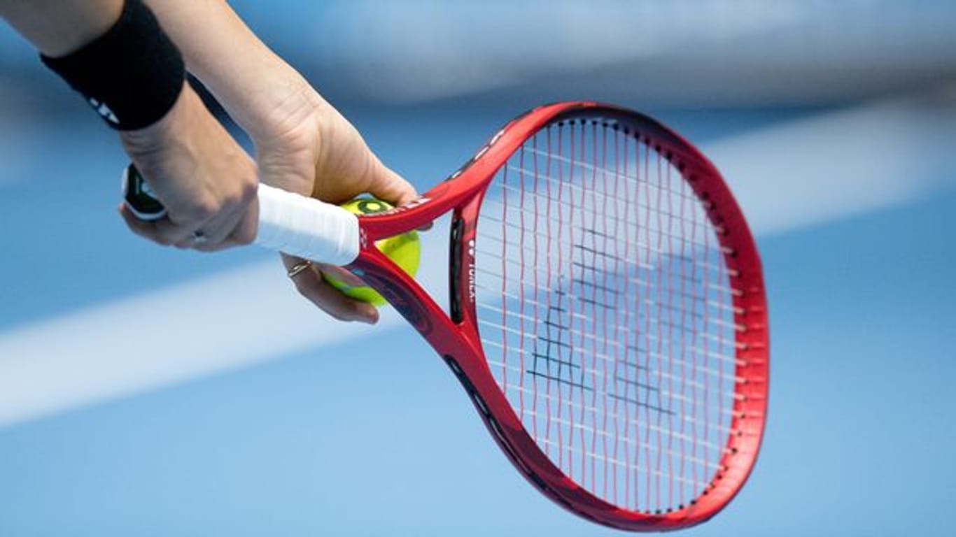 Eine Person hält einen Tennisschläger und einen Tennisball in der Hand (Symbolbild): Ein Trainer wurde verurteilt.