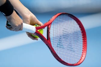 Eine Person hält einen Tennisschläger und einen Tennisball in der Hand (Symbolbild): Ein Trainer wurde verurteilt.