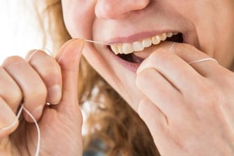 Zahnseide benutzen: Mit Vorsicht die Zahnflächen entlanggleiten – so lautet die Grundregel.