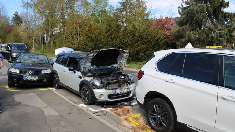 Ein beschädigter Mini steht zwischen mehreren Autos an der Romaneyer Straße in Bergisch Gladbach: Dort ist es zu einem Unfall gekommen.