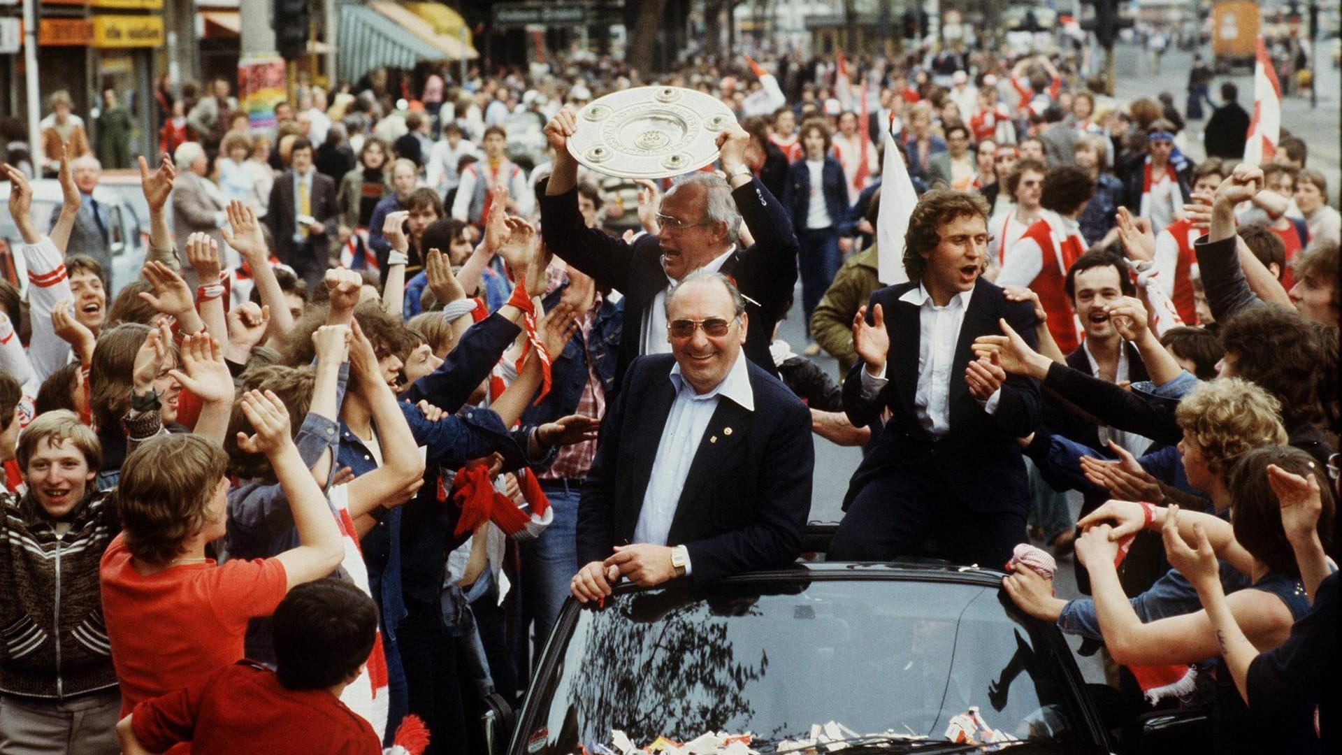 Trainer Hennes Weisweiler mit der Meisterschale beim Autokorso durch die Kölner Innenstadt: Mit von der Partie Präsident Peter Weiand vorn und Heinz Flohe.