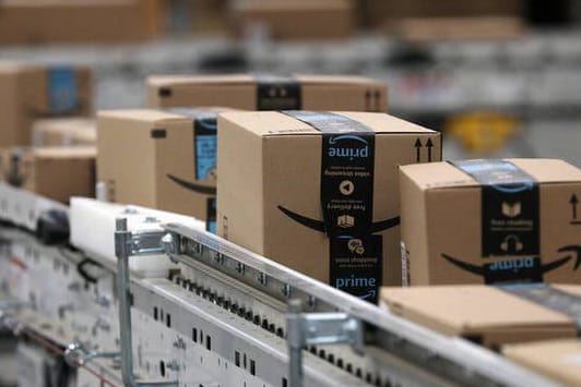 Amazon-Pakete auf Fließband (Symbolbild): Der Versandkonzern hat die Löhne angehoben.