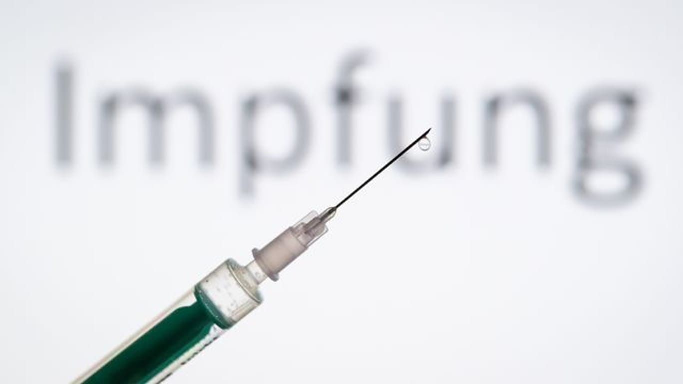 Eine Spritze wird vor den Schriftzug "Impfung" gehalten (Symbolbild): Auch Supermarktangestellte oder enge Kontaktpersonen von Pflegebedürftigen können sich bald impfen lassen.