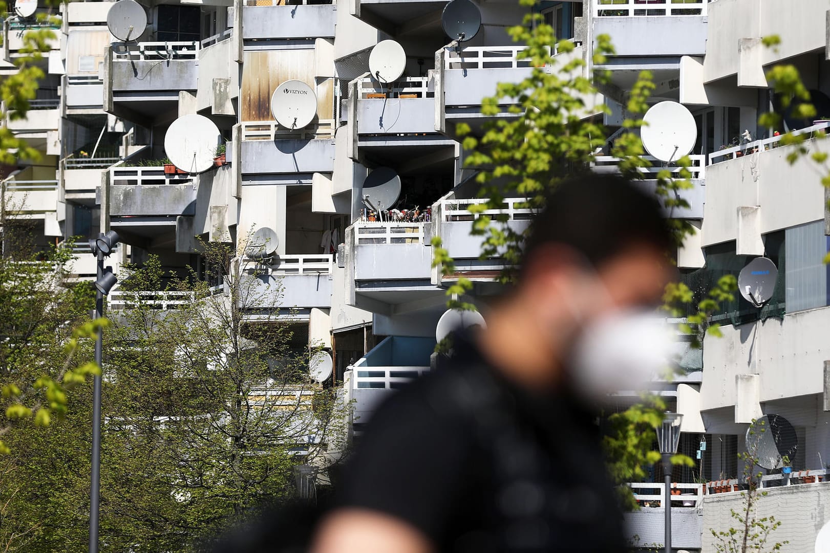 Ein Mann geht mit Schutzmaske an einem Hochhaus vorbei: Die Stadt Köln will in Stadtteilen mit hohem Infektionsrisiko bevorzugt impfen.