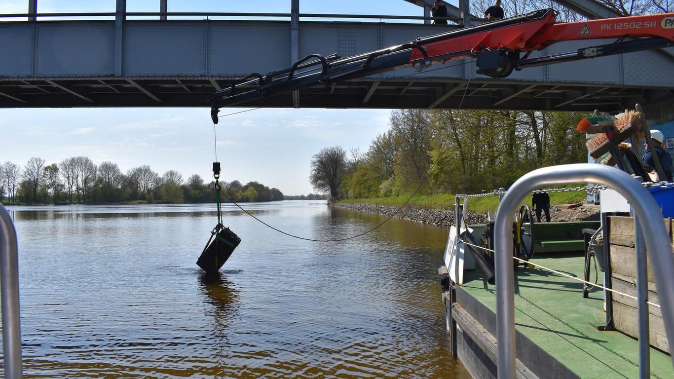 Mit dem Kran eines Bootes des Wasserstraßen- und Schifffahrtamtes Weser wird ein Tresor aus dem Wasser gehoben: Die Polizei war mit Spezialgerät und Tauchern im Einsatz.
