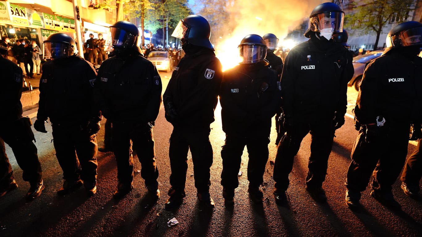 Polizisten mit Schutzhelmen stehen vor einem Brand in der Sonnenallee in Neukölln:Bei der "Demonstration zum revolutionären 1. Mai" kam es in Berlin zu Auseinandersetzungen und Randale.