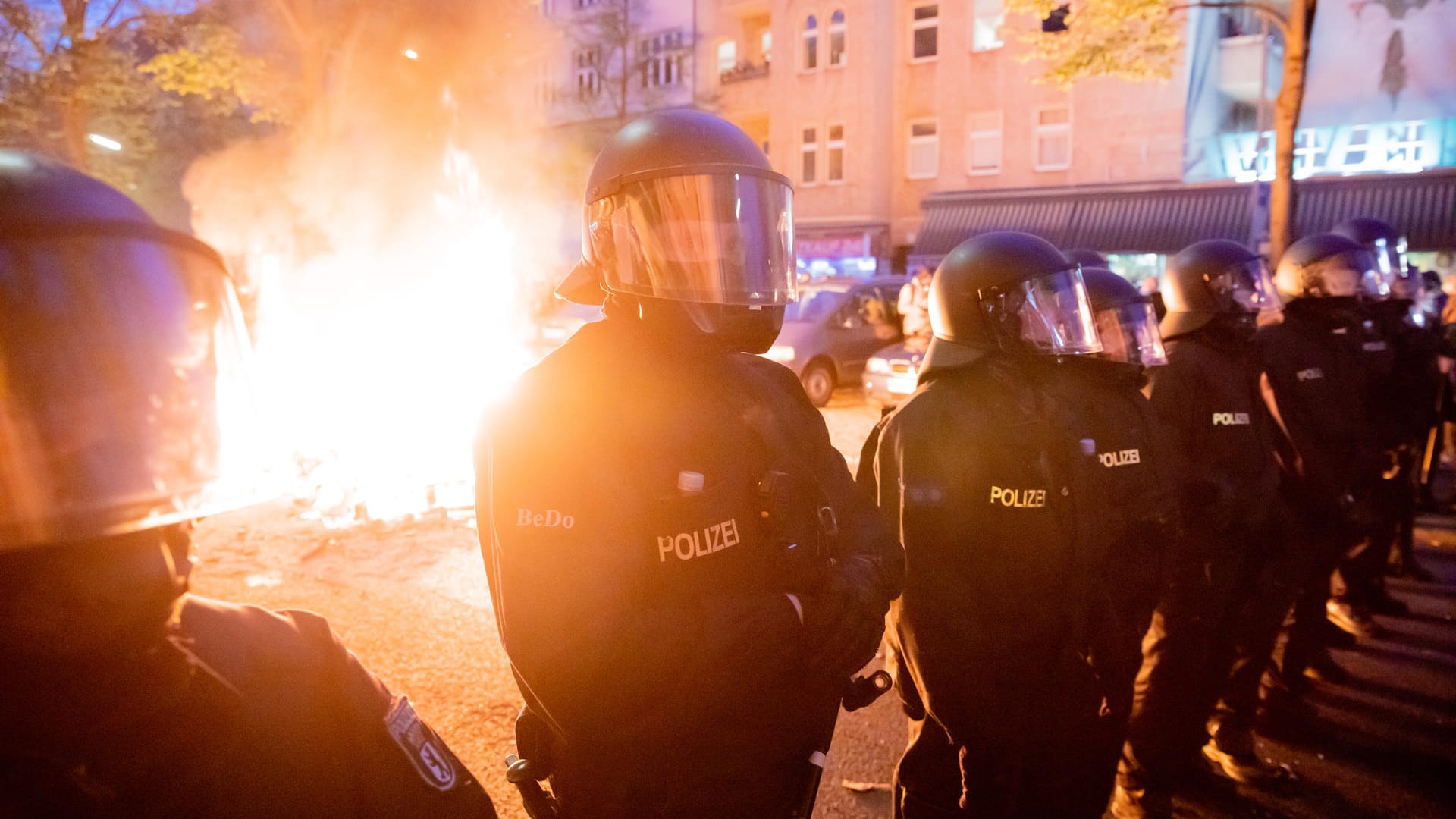 Polizisten stehen am Rande der Demonstration vor einem Feuer auf der Straße: Mehrere Einsatzkräfte wurden am Samstag mit Steinen, Flaschen und Böllern beworfen.
