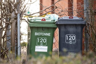 Eine Biotonne steht neben einer schwarzen Mülltonne: Auf der Flucht vor der Polizei hat sich ein Mann in einer Mülltonne versteckt.