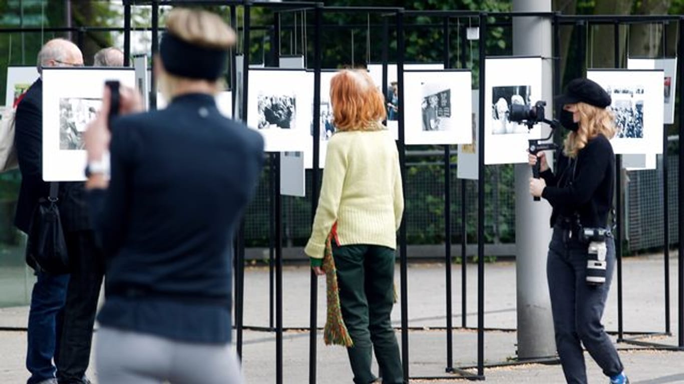 Spaziergänger schauen sich die Outdoor-Fotoausstellung im Rahmen der Ruhrfestspiele am Festspielhaus an.