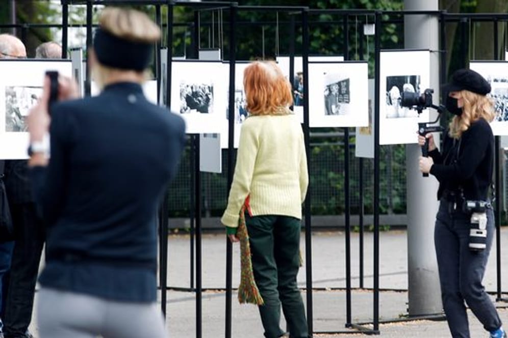 Spaziergänger schauen sich die Outdoor-Fotoausstellung im Rahmen der Ruhrfestspiele am Festspielhaus an.