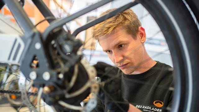 Im Februar hat er seine Ausbildung zum Zweiradmechatroniker abgeschlossen: Stefan Borschert setzt ein neues Hinterrad an einem E-Lastenrad ein.