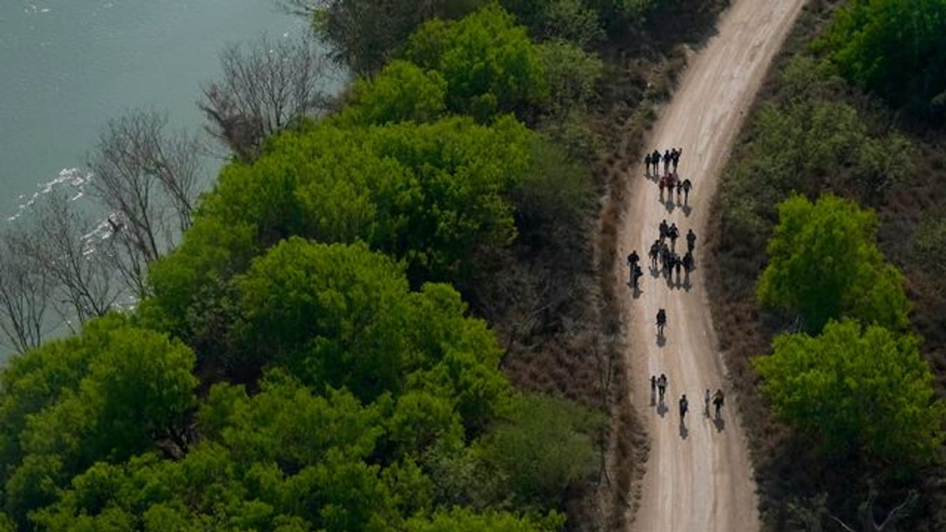 Migranten gehen einen Feldweg in Mission (Texas) entlang, nachdem sie die Grenze zwischen Mexiko und den USA überquert haben.