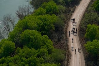 Migranten gehen einen Feldweg in Mission (Texas) entlang, nachdem sie die Grenze zwischen Mexiko und den USA überquert haben.