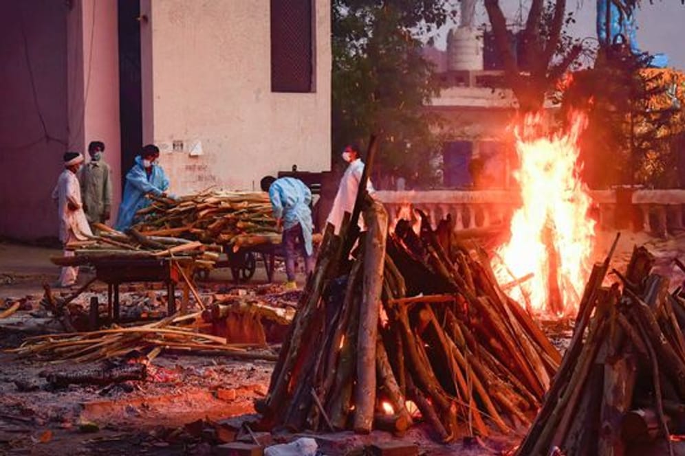 Angehörige eines an den Folgen des Coronavirus Verstorbenenen sammeln in Neu Delhi Holz für die Einäscherung.