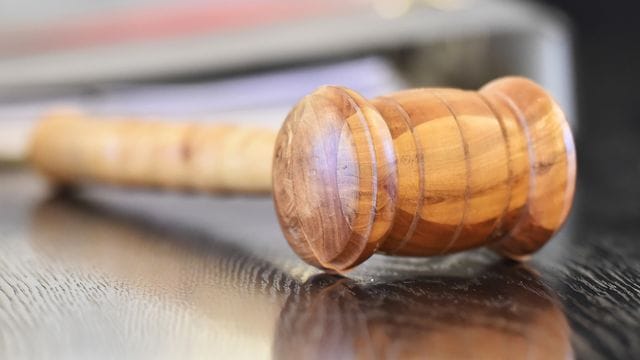 Ein Richterhammer aus Holz auf einer Richterbank. (Symbolfoto) Ein Richterhammer aus Holz auf einer Richterbank. (Symbolfoto)