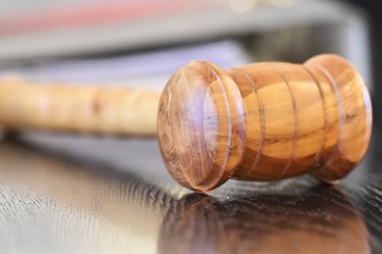 Ein Richterhammer aus Holz auf einer Richterbank. (Symbolfoto)