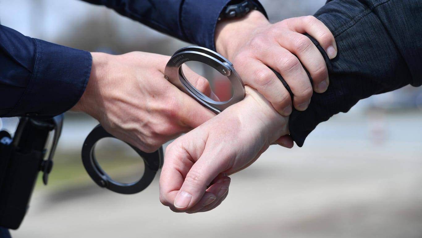 Ein Polizist legt Handschellen an (Symbolbild): In Köln ist ein bewaffneter Mann festgenommen worden.