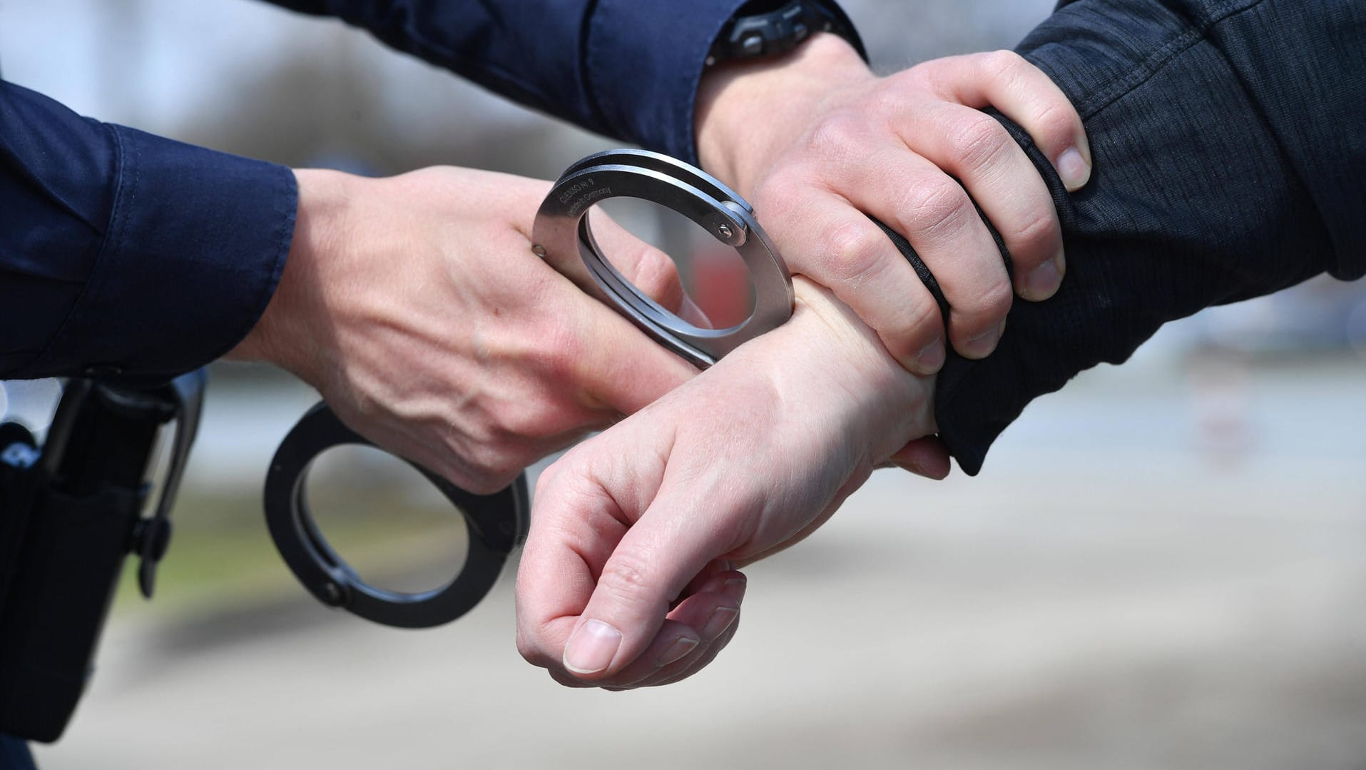 Ein Polizist legt Handschellen an (Symbolbild): In Köln ist ein bewaffneter Mann festgenommen worden. Ein Polizist legt Handschellen an (Symbolbild): In Köln ist ein bewaffneter Mann festgenommen worden.