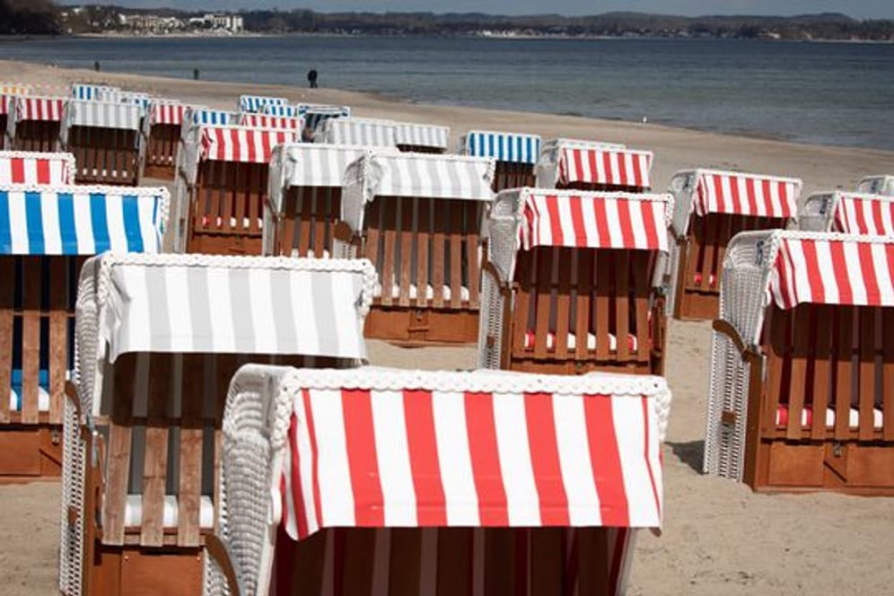 Geschlossene Strandkörbe stehen auf dem fast menschenleeren Strand in Timmendorfer Strand an der Ostsee.
