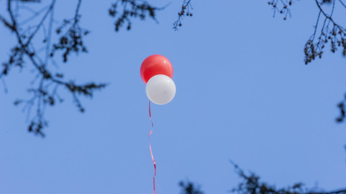 Lufballons in rot und weiß steigen bei der Trauerfeier von Willi Herren am Melatenfriedhof in den Himmel: Der Schauspieler und Sänger war am 20. April verstorben und am 5. Mai beerdigt worden.