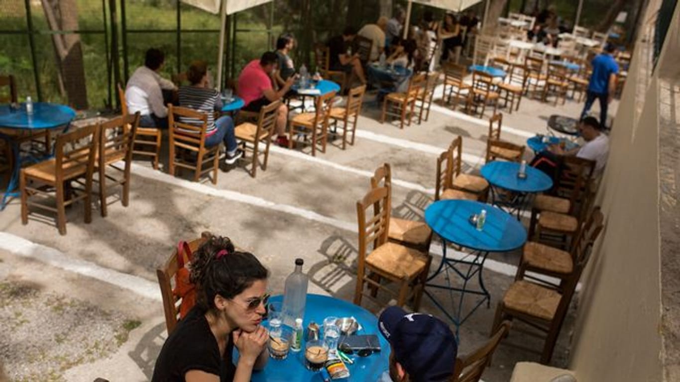 Gäste sitzen in einem Café im Stadtteil Monastiraki im Zentrum Athens.