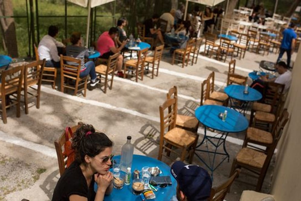 Gäste sitzen in einem Café im Stadtteil Monastiraki im Zentrum Athens.
