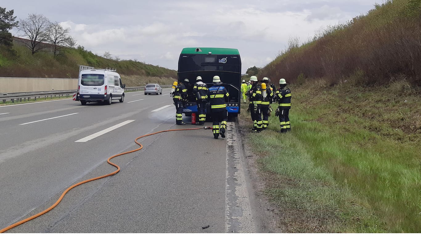 Feuerwehrleute löschen den Brand in dem Bus: Auf der Autobahn hat der Motorraum Feuer gefangen.