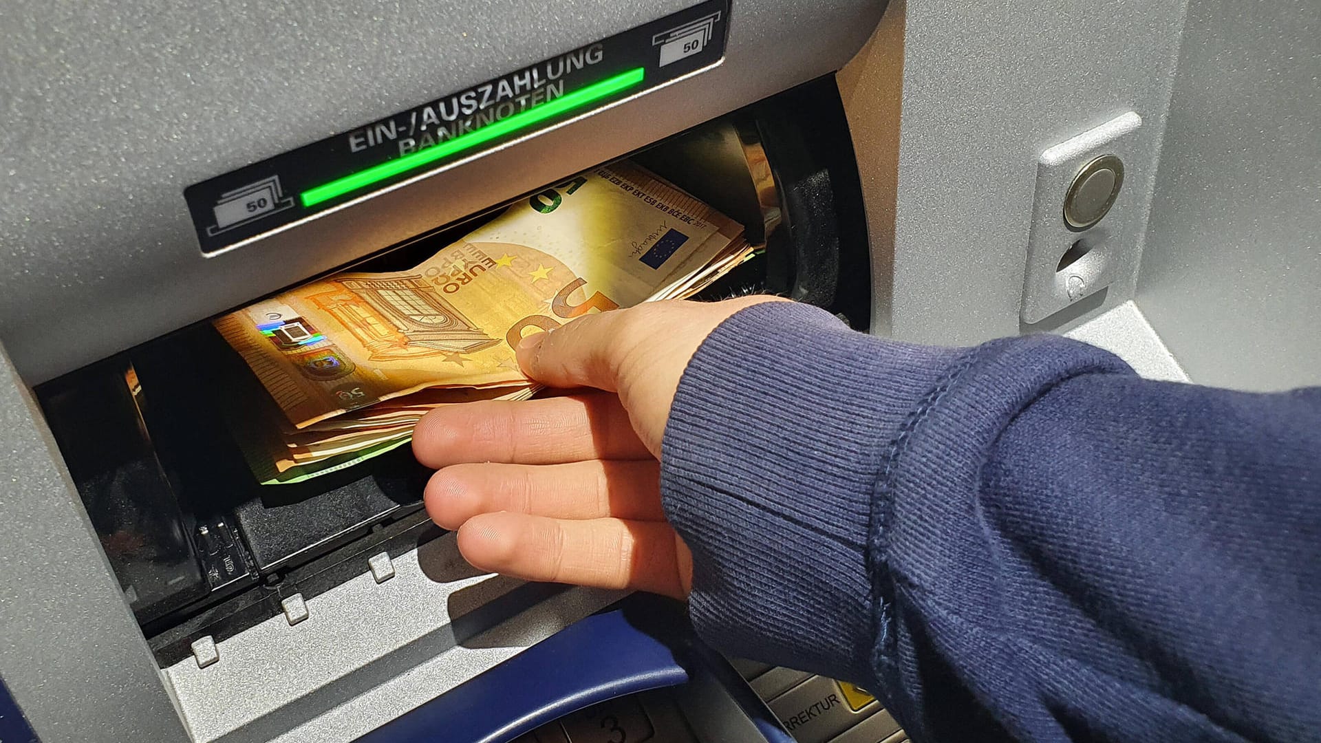 Ein Mann hebt Geld ab (Symbolbild): In Dortmund hat ein ziviler Polizist einen Betrüger festgehalten.