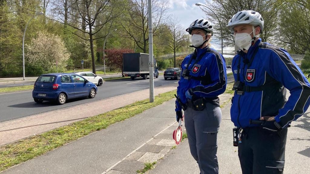 Zwei Polizeibeamte stehen am Straßenrand und tragen Fahrrradhelme und eine Maske: Bei der länderübergreifenden Aktion wurden viele Verstöße festgestellt.