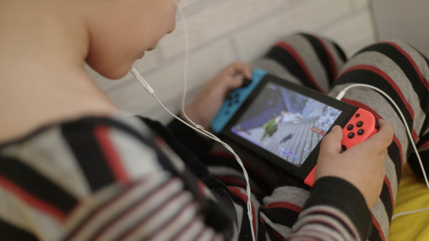 Ein 8-jähriger Junge spielt auf dem Bett ein Videospiel auf der Spielekonsole Switch: Der Erfolg der Spielekonsole Switch in der Corona-Pandemie hat Nintendo ein starkes Jahr beschert.